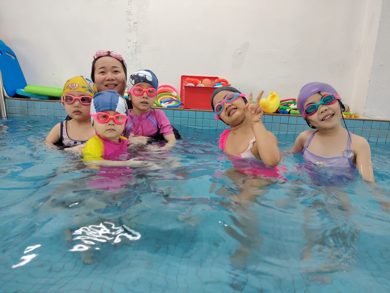 A group of children in colourful swim caps lined up for their lesson