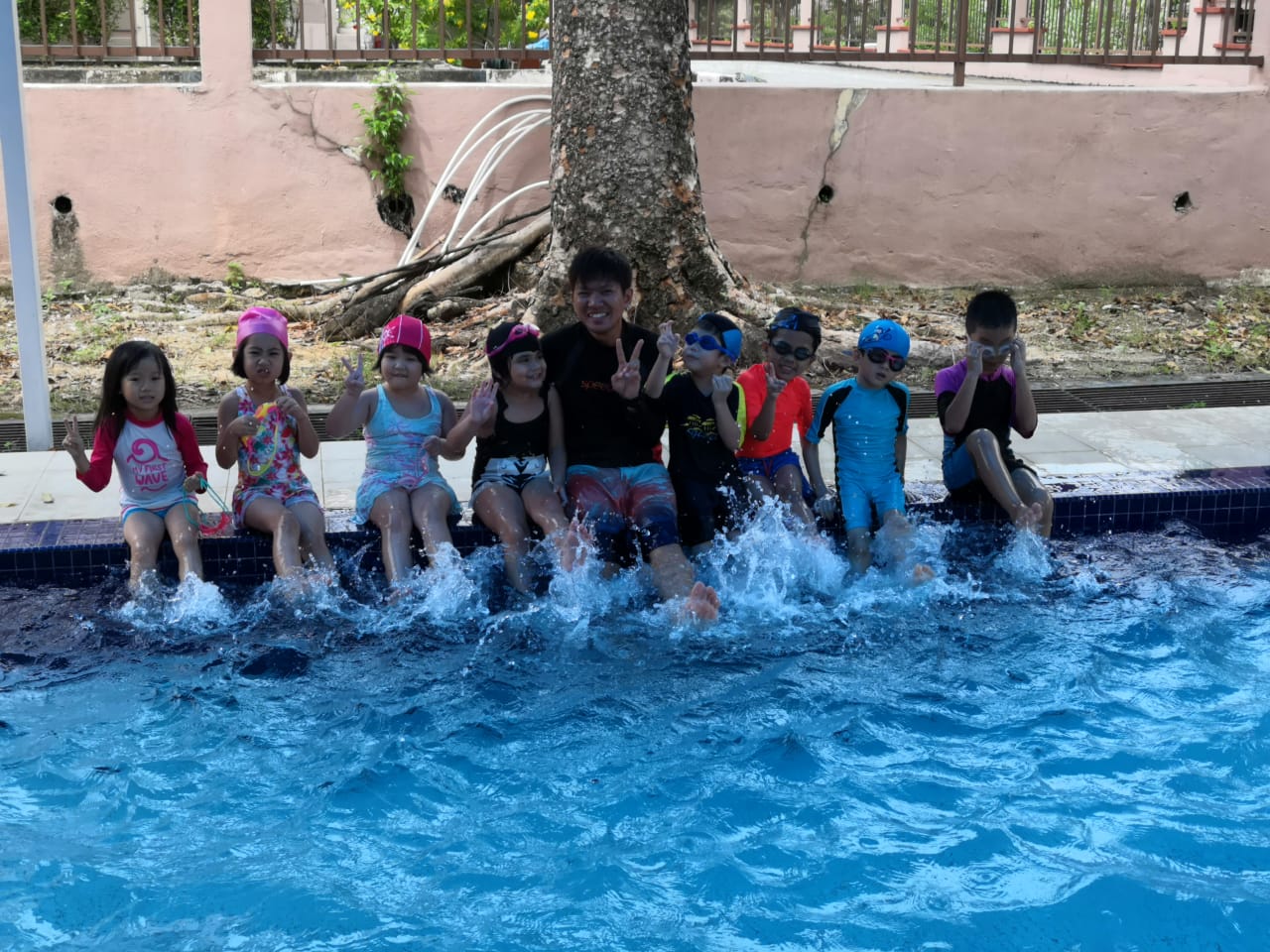 Children smiling together in the pool during a group class